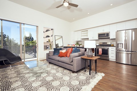 a living room with a couch and a kitchen with stainless steel appliances